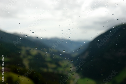 Raindrops on the window glass with blurred mountain landscape in the background