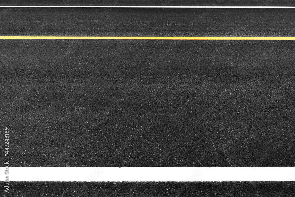 Fototapeta premium Close up black asphalt road surface texture with a separation yellow and white line.