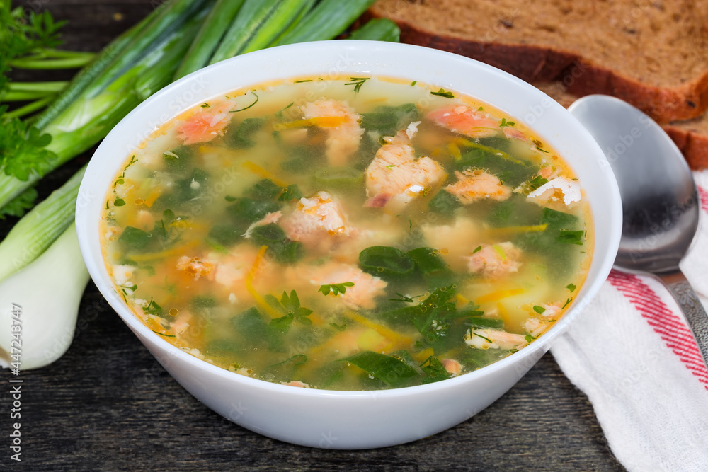 Bowl of clear salmon soup on dark surface, close-up Bowl of clear salmon soup on dark surface, close-up