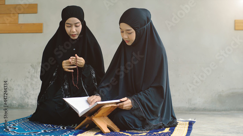 Portrait of an Asian Muslim women in a daily prayer at home reciting Surah al-Fatiha passage of the Qur'an in a single act of Sujud called a Sajdah or prostration