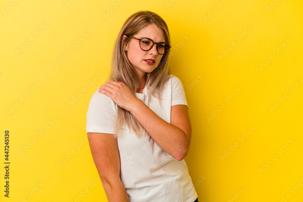 Young russian woman isolated on yellow background having a shoulder pain.