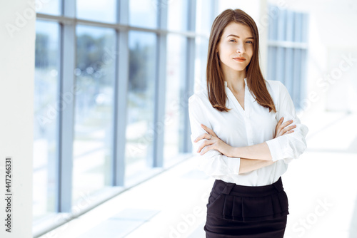 Free Download Beautiful female specialist with arms crossed standing in modern office and smiling charmingly. Working on design, data analysis, plan strategy. Business people concept - GFXLoad
