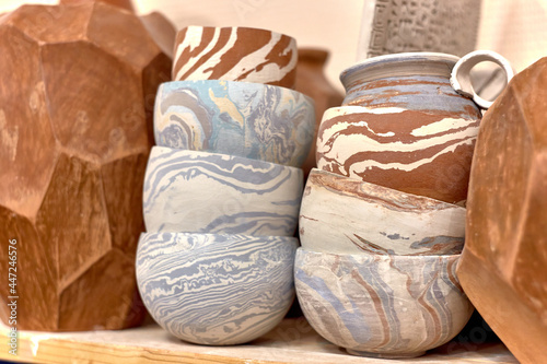 A stack of ready-made ceramics using Japanese technique Nerikomi made of white, red and blue clay dries on a shelf