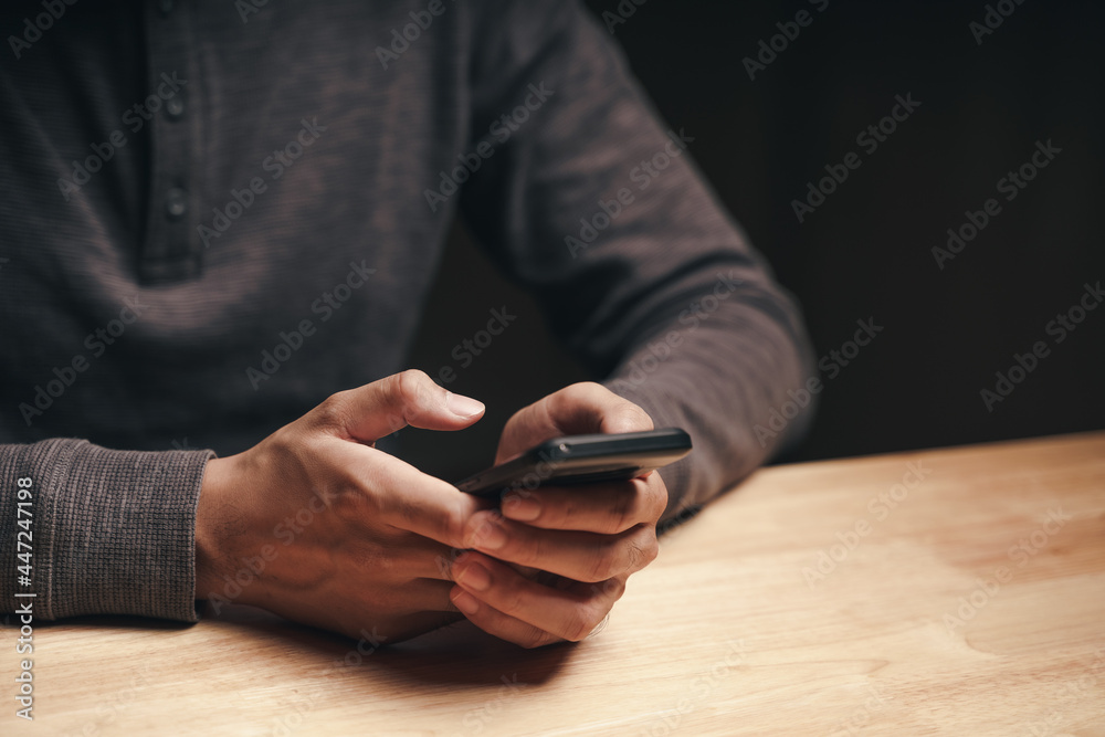 Closeup of a man using a smartphone on the wooden table, searching, browsing, social media, message, email, internet digital marketing, online shopping.. Closeup of a man using a smartphone on the wooden table, searching, browsing, social media, message, email, internet digital marketing, online shopping..