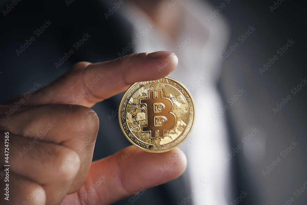 Handsome Investor Businessman in black suit holding a golden bitcoin on dark background, trading, Cryptocurrency, Digital virtual currency, alternative finance and investment Concept.. Handsome Investor Businessman in black suit holding a golden bitcoin on dark background, trading, Cryptocurrency, Digital virtual currency, alternative finance and investment Concept..