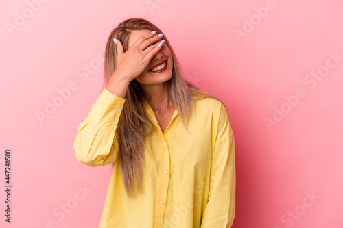 Young russian woman isolated on pink background laughs joyfully keeping hands on head. Happiness concept. © Asier
