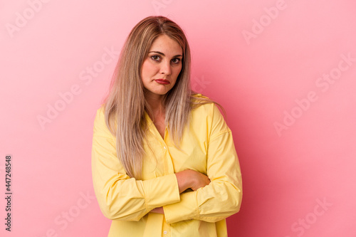 Young russian woman isolated on pink background shrugs shoulders and open eyes confused.