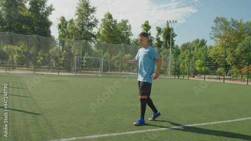 Young attractive soccer player in sportswear requesting substitution because of football cramping during training match at daybreak. Sportsman getting injury, teammate changing injured player photo