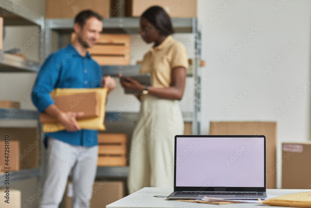 Blank laptop screen in warehouse with people working in background, small business and shipping service concept, copy space Blank laptop screen in warehouse with people working in background, small business and shipping service concept, copy space