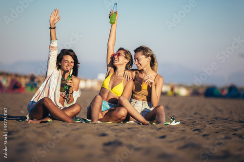 Group of young women friends drinking together on the beach