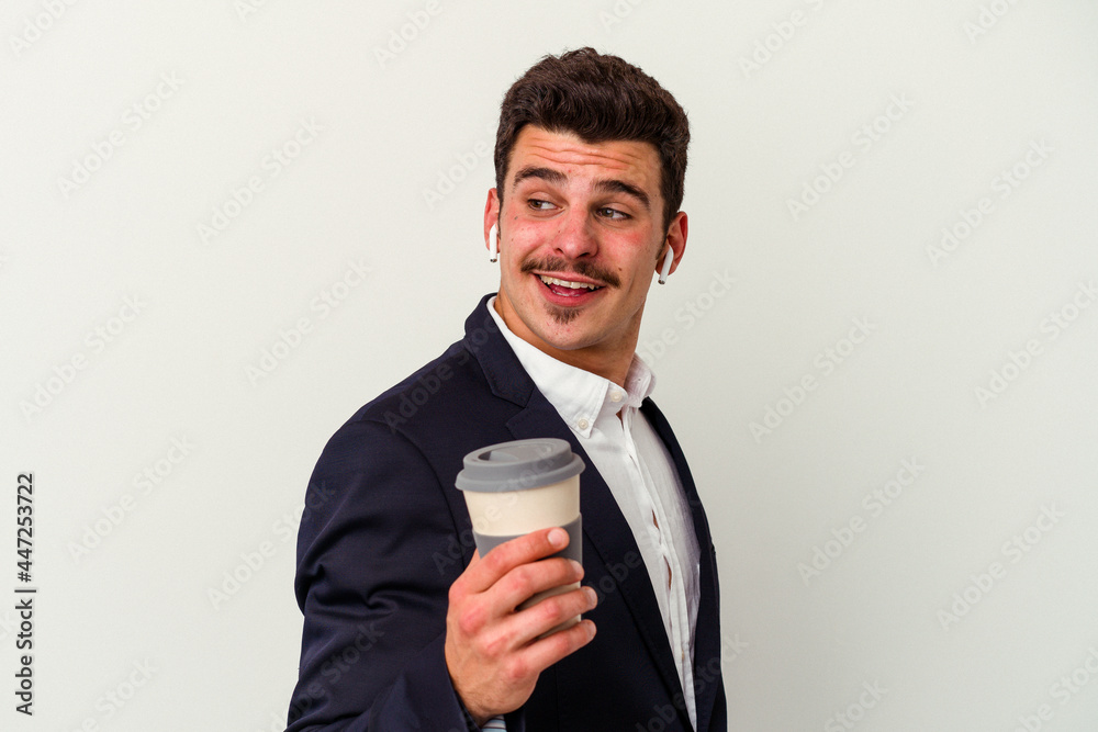 Young business caucasian man wearing wireless headphones and holding take way coffee isolated on white background looks aside smiling, cheerful and pleasant. Young business caucasian man wearing wireless headphones and holding take way coffee isolated on white background looks aside smiling, cheerful and pleasant.