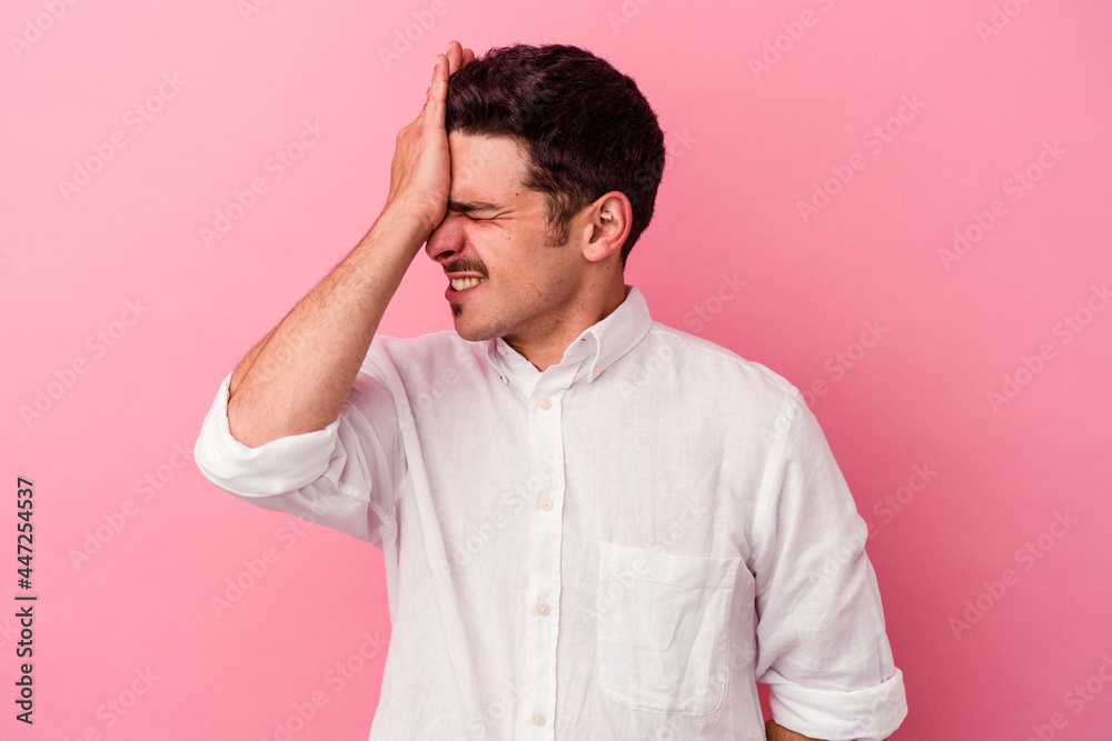 Young caucasian man isolated on pink background forgetting something, slapping forehead with palm and closing eyes.
