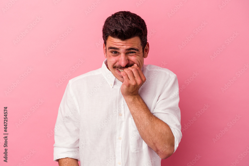 Young caucasian man isolated on pink background biting fingernails, nervous and very anxious. Young caucasian man isolated on pink background biting fingernails, nervous and very anxious.
