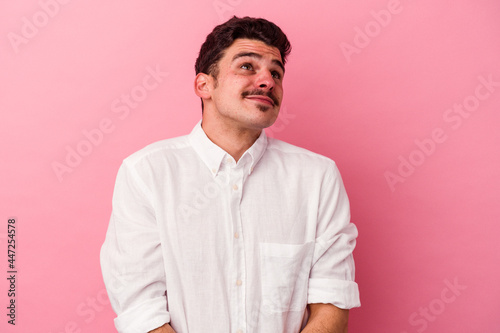 Young caucasian man isolated on pink background dreaming of achieving goals and purposes