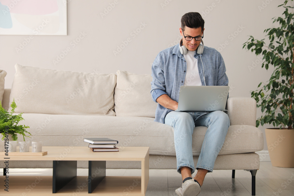 Man with laptop and headphones sitting on sofa at home Man with laptop and headphones sitting on sofa at home