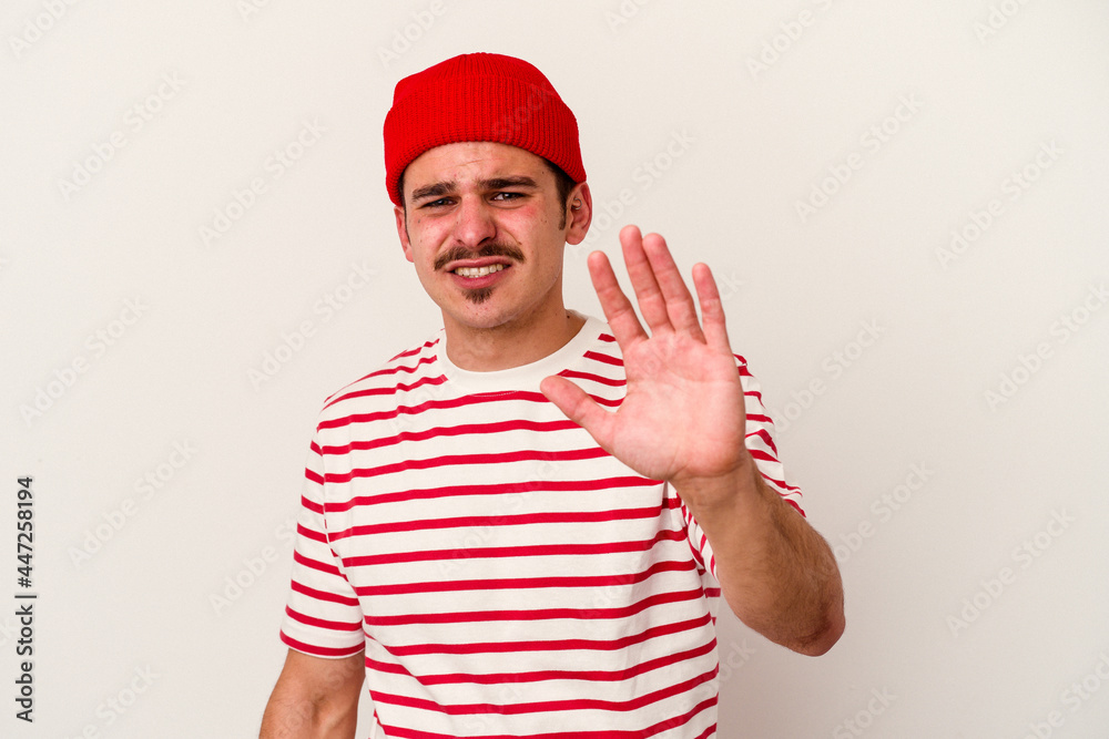 Naklejka premium Young caucasian man isolated on white background rejecting someone showing a gesture of disgust.