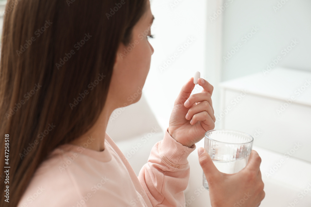 Young woman with glass of water taking pill at home, closeup Young woman with glass of water taking pill at home, closeup