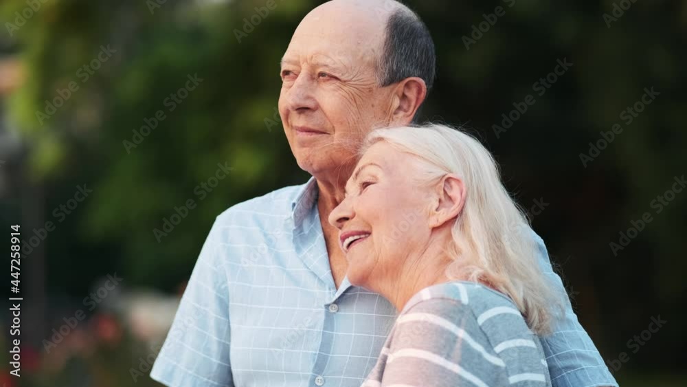 A lovely elderly couple man and woman enjoy landscape in the park while walking outdoors A lovely elderly couple man and woman enjoy landscape in the park while walking outdoors