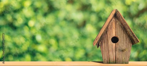 Wooden bird house with copy space on green nature background