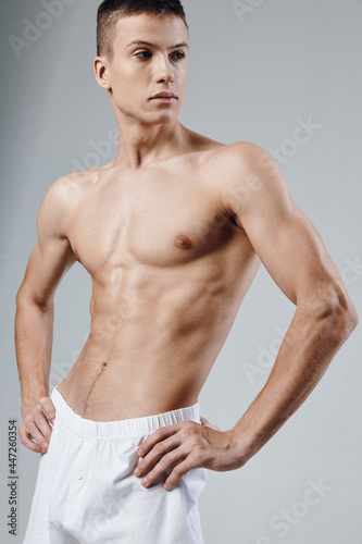 athlete in white shorts holds hands on belt gray background cropped view