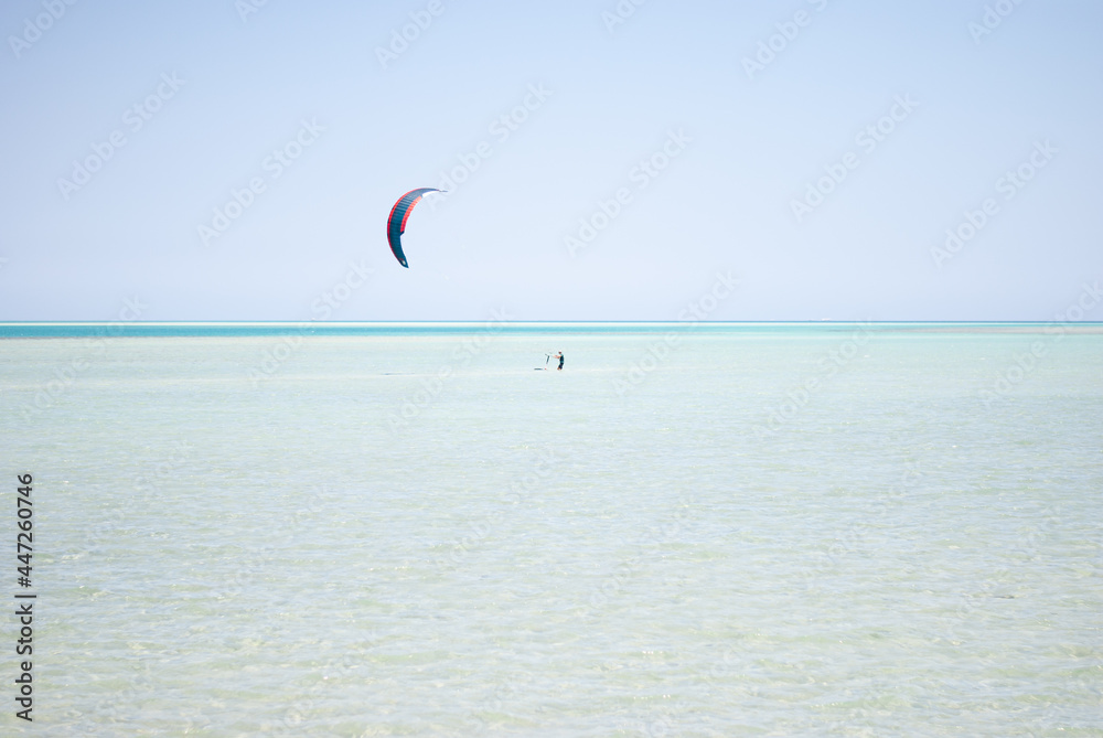 The man at the sea is engaged in kitesurfing. A lone kiter goes in for sports.