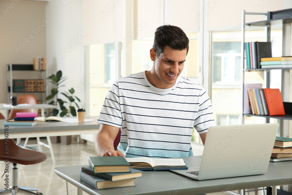 Man with laptop studying at table in library