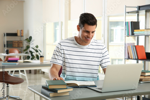 Man with laptop studying at table in library