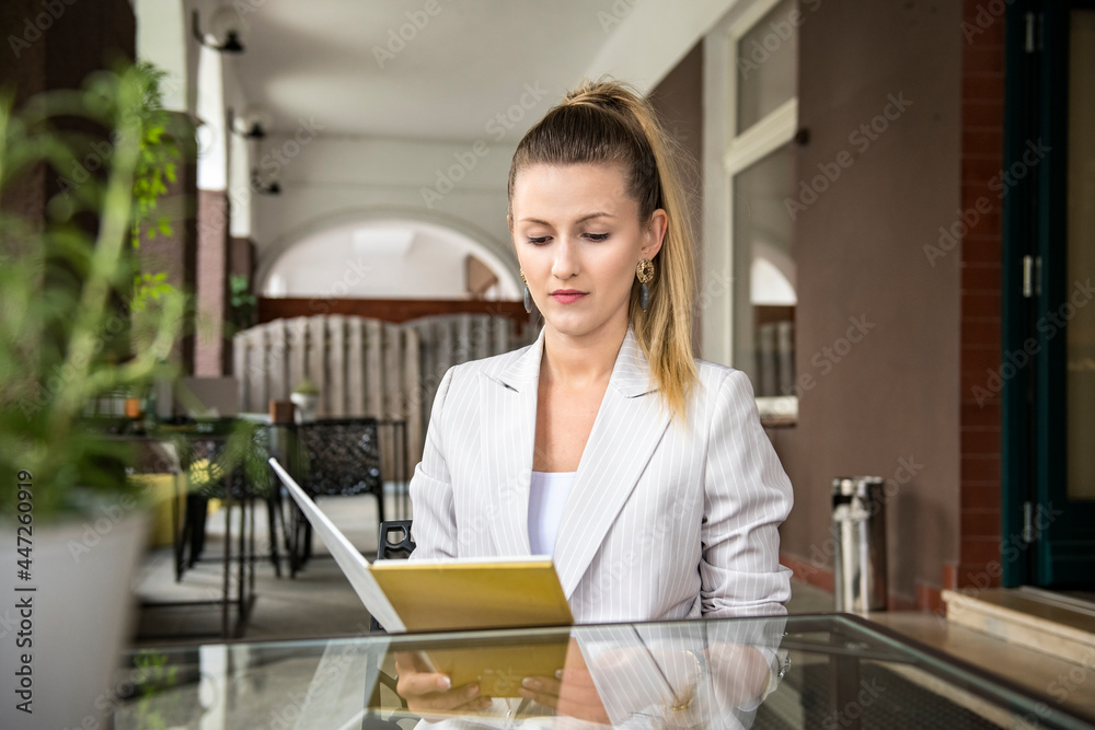 Young elegant beautiful woman is looking at a menu in a cafe Young elegant beautiful woman is looking at a menu in a cafe