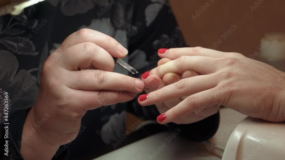 Female manicure applying red nail polish