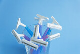 Set of multi-colored disposable razors in a glass on a blue background