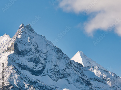 Snow covered summit of Besso mountain  left  and Ober Gabelhorn  right  in front of blue sky