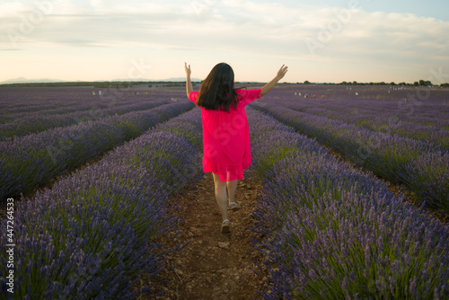 back portrait of young happy and beautiful woman in Summer dress enjoying nature running free and playful outdoors at purple lavender flowers field in romantic beauty concept