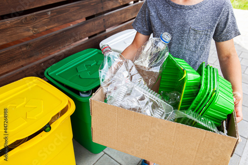 The boy collect the plastic trash into the paper box for recycling