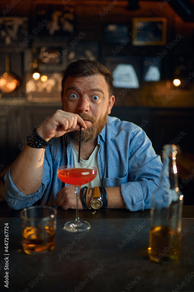 Funny man drinks alcohol coctail at counter in bar Funny man drinks alcohol coctail at counter in bar