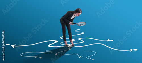 Choice and find your way concept with businesswoman looking through a magnifying glass on arrow roads drawn on bright blue surface.
