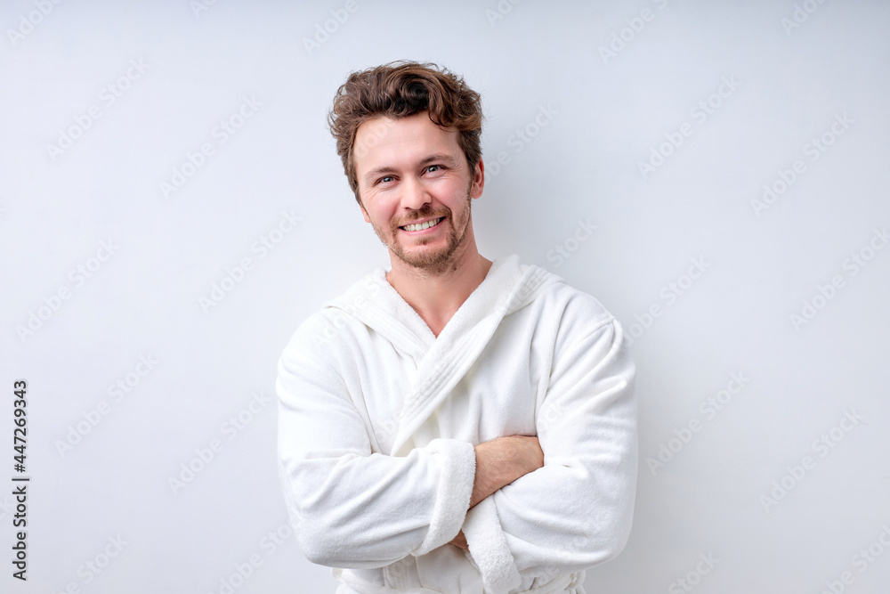 Portrait of handsome smiling guy in white bathrobe looking at camera, with arms crossed folded, caucasian bearded man in good mood. people lifestyle, human emotions, everyday routine concept Portrait of handsome smiling guy in white bathrobe looking at camera, with arms crossed folded, caucasian bearded man in good mood. people lifestyle, human emotions, everyday routine concept