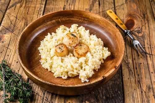 Italian Risotto with Scallops in a pan. wooden background. Top view
