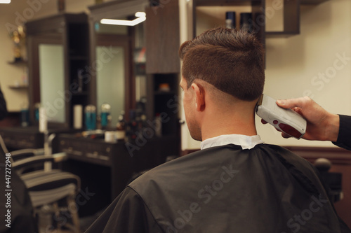 Professional hairdresser making stylish haircut in salon, back view