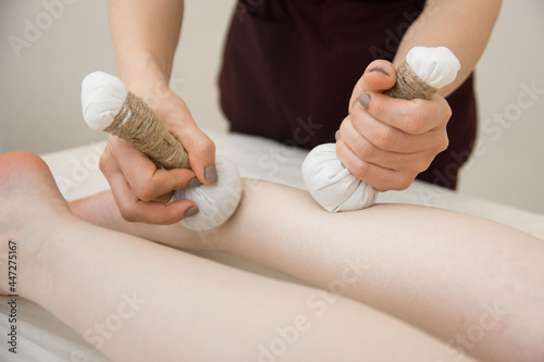 the masseur uses herbal bags for a relaxing spa wellness treatment