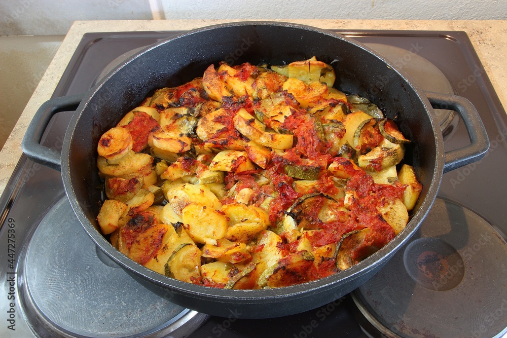 Baked vegetables of potatoes, zucchini, and tomato sauce in a pan. Greek dish of Baked vegetables of potatoes, zucchini, and tomato sauce in a pan. Greek dish of