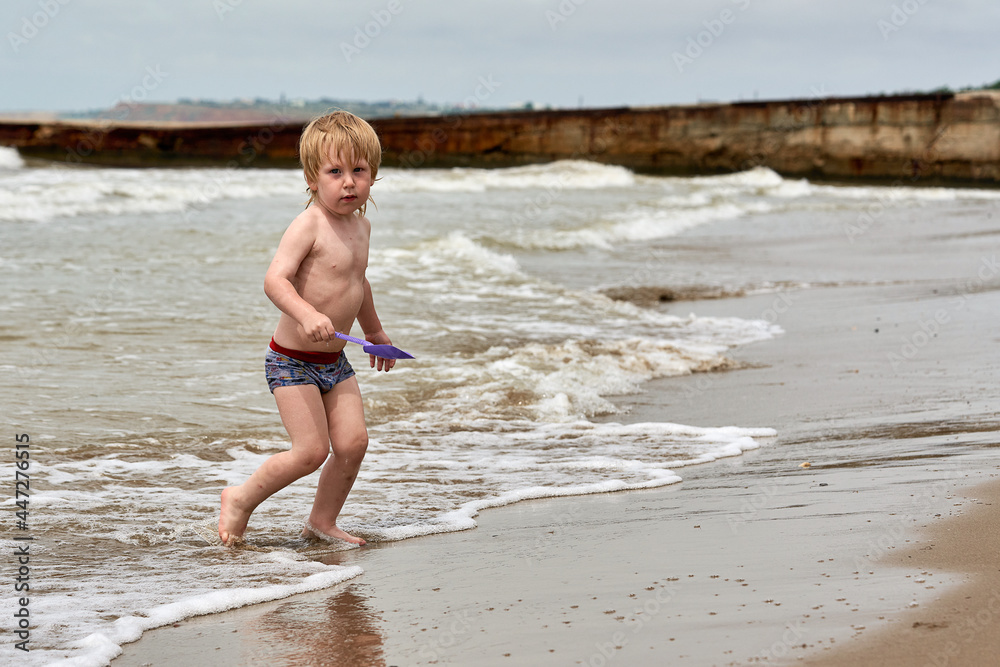 A little boy runs along the sandy beach along the seashore A little boy runs along the sandy beach along the seashore