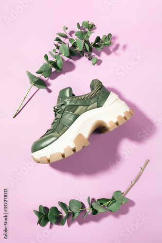 Chunky sole green trainer sneaker with eucalyptus branches framing it, on pink, top view - flatlay