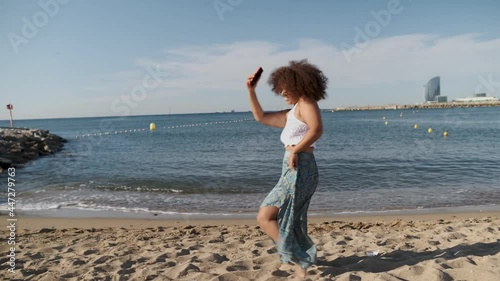 young curvy real woman with afro hair dancing for viral video at Barcelona beach photo