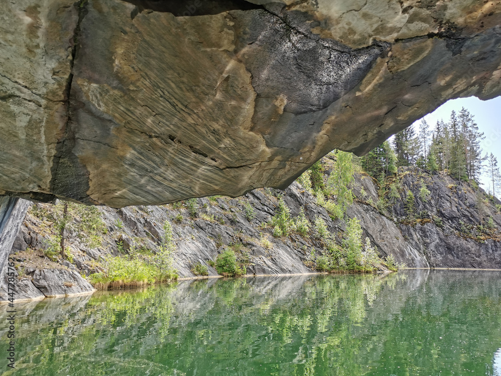 View from the grotto with a textured ceiling and reflections from the water on the steep slope of the flooded Marble Canyon in the mountain park Ruskeala.