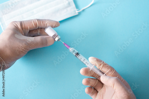 A close up of the vaccine and the syringe in the doctor's hand