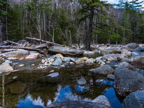 Reflection of the sky and trees in the slower flowing crystal clear Pemigewasset River in spring on the Lincoln Forest trail in the White Mountains, Lincoln, NH