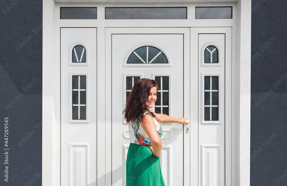 Front door. Young woman holds doorknob on front door PVC Front door. Young woman holds doorknob on front door PVC
