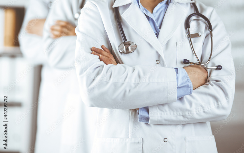 Group of modern doctors standing as a team with arms crossed in hospital office and ready to help patients. Medical help, insurance in health care, best disease treatment and medicine concept