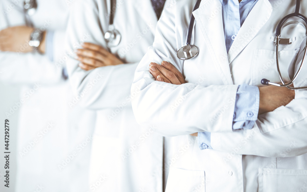 Group of modern doctors standing as a team with arms crossed in hospital office and ready to help patients. Medical help, insurance in health care, best disease treatment and medicine concept Group of modern doctors standing as a team with arms crossed in hospital office and ready to help patients. Medical help, insurance in health care, best disease treatment and medicine concept
