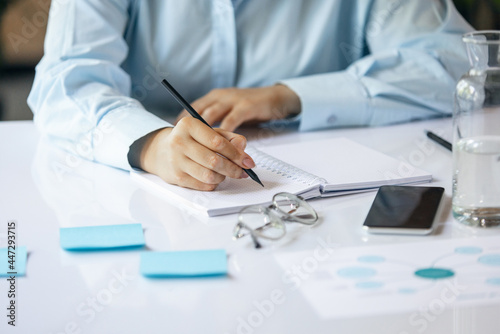 Cropped image of young woman, business lady during working office day. Using laptop, modern gadgets. Remote working. Workplace at office with PC, devices.